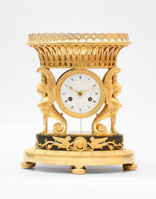 A French Empire ormolu urn mantel clock with griffins, circa 1800 by Artista Desconocido