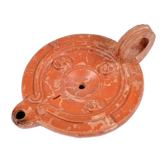  A Roman terracotta red slip ware oil lamp with theatre masks by Artista Sconosciuto